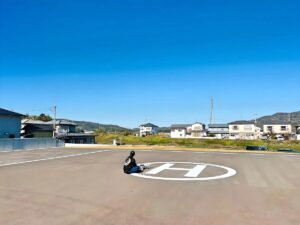 ヘリパットに座り込み、取得したデータをダウンロード中